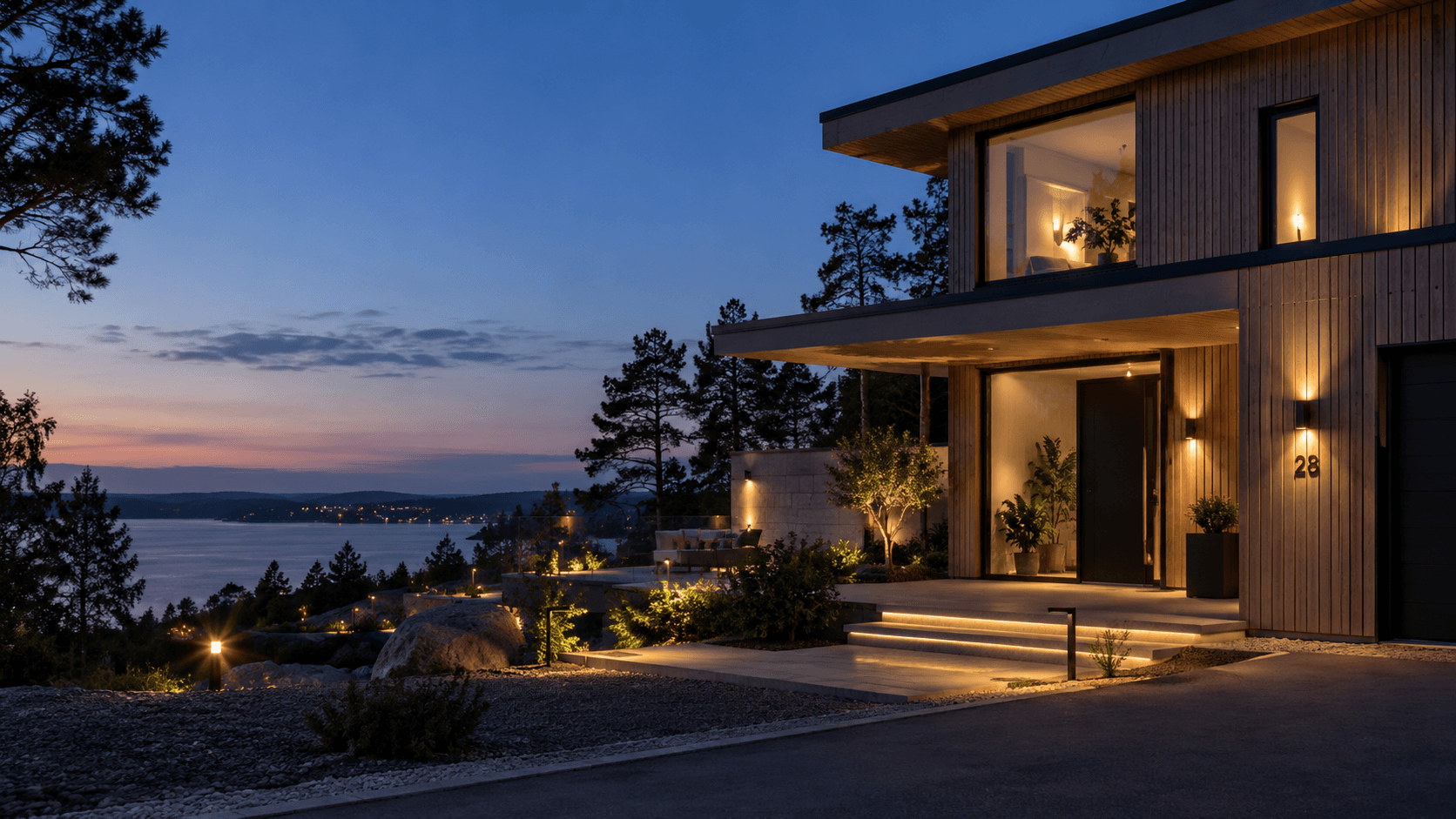 Modern villa i skymning med genomtänkt utomhusbelysning vid entré och trädgård